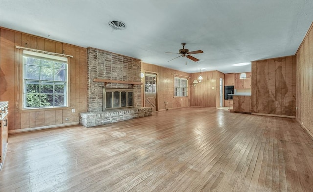 1500 Galde St, College Station, TX 77840 - unfurnished living room featuring light wood-type flooring, a ceiling fan, wood walls, and a fireplace