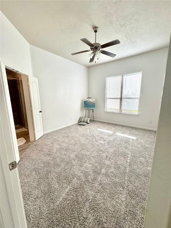 carpeted empty room featuring ceiling fan, a textured ceiling, and baseboards