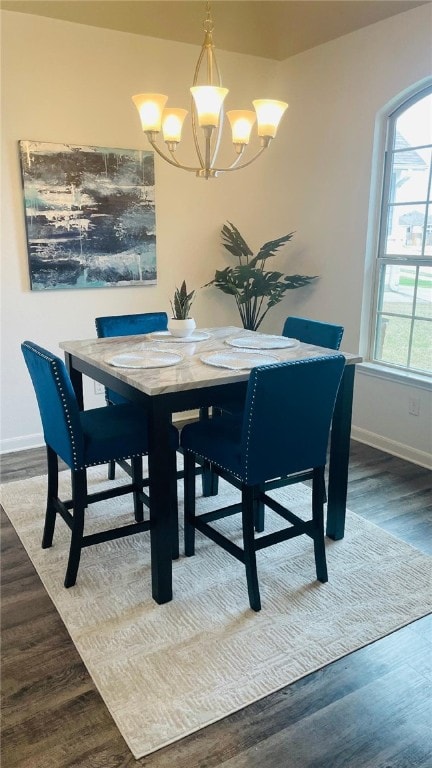 dining area featuring a chandelier, baseboards, and wood finished floors