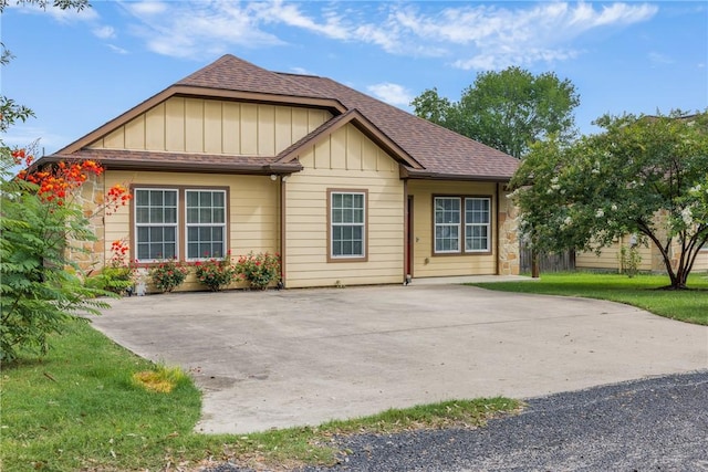 4002 High St, Bryan, TX 77808 - view of front of property with board and batten siding, roof with shingles, stone siding, and a front lawn