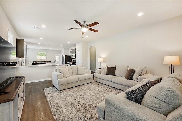 living room featuring ceiling fan and dark hardwood / wood-style flooring