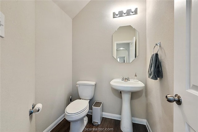 bathroom featuring hardwood / wood-style flooring, toilet, sink, and vaulted ceiling