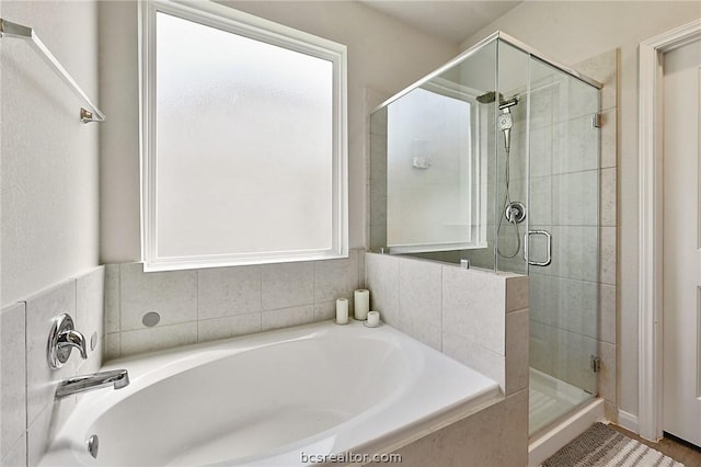 bathroom featuring plus walk in shower and a healthy amount of sunlight