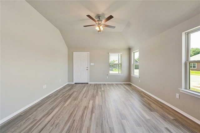 empty room featuring ceiling fan, vaulted ceiling, and light wood-type flooring