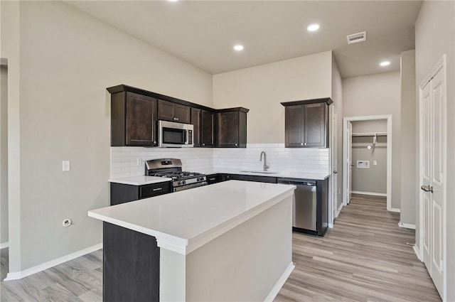 kitchen with dark brown cabinets, stainless steel appliances, sink, and a kitchen island