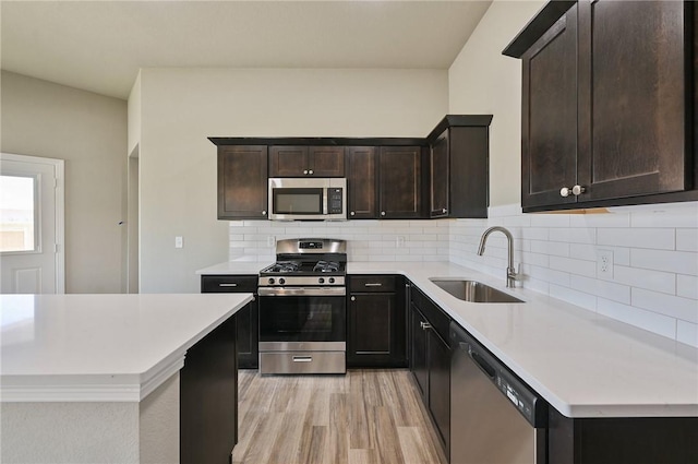 kitchen featuring sink, appliances with stainless steel finishes, backsplash, dark brown cabinets, and light wood-type flooring