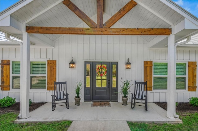 view of exterior entry featuring board and batten siding and covered porch