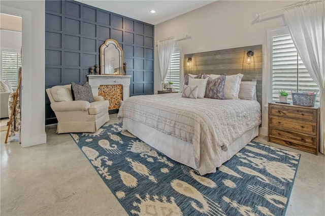 bedroom featuring recessed lighting, multiple windows, finished concrete floors, and a decorative wall