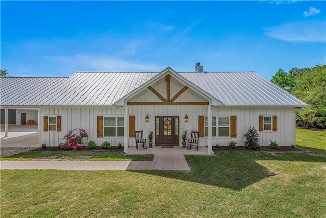 back of property with board and batten siding, a yard, a chimney, and metal roof