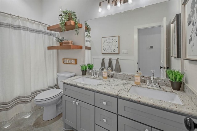 full bath with double vanity, toilet, curtained shower, and a sink