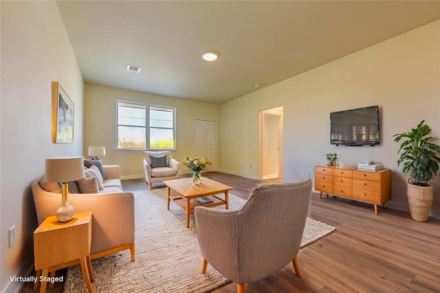 living room with baseboards, visible vents, and wood finished floors