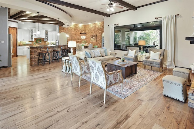 living room featuring ceiling fan, brick wall, light hardwood / wood-style flooring, and beamed ceiling