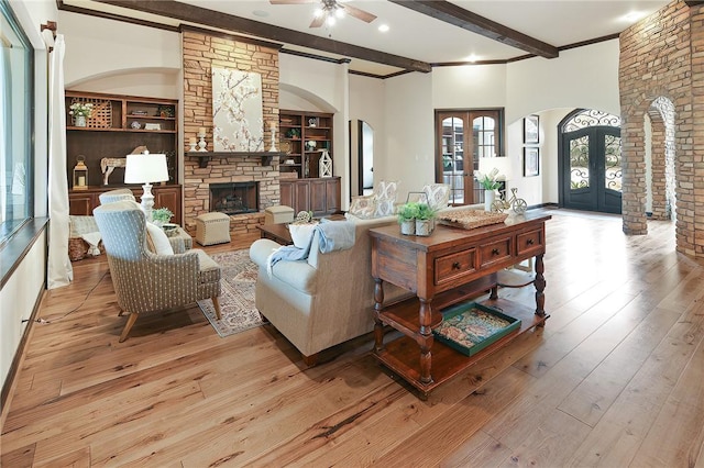 living room with french doors, built in features, ceiling fan, light hardwood / wood-style flooring, and beam ceiling