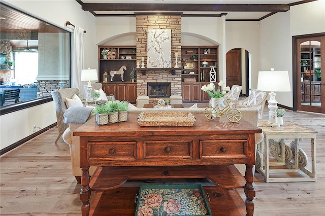 living room with light hardwood / wood-style flooring, built in features, beamed ceiling, and a fireplace