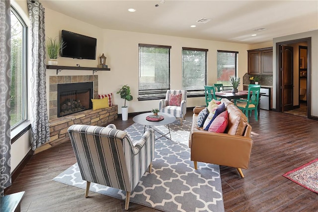 living room with dark hardwood / wood-style floors and a stone fireplace