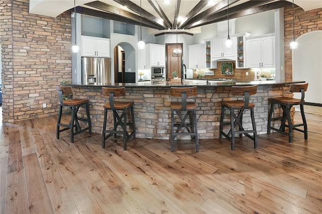 interior space featuring tasteful backsplash, light wood-type flooring, stainless steel appliances, and white cabinetry