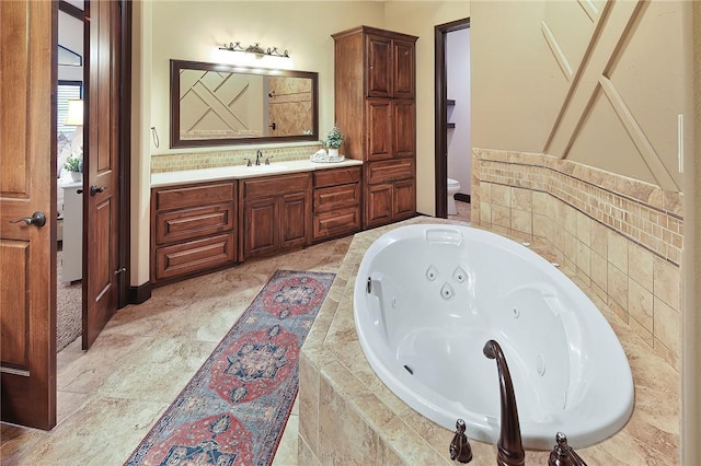 bathroom featuring tiled bath, toilet, and vanity