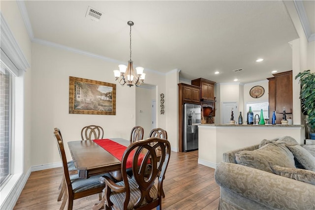 dining room featuring light wood-style flooring, recessed lighting, visible vents, baseboards, and ornamental molding