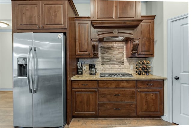 kitchen featuring appliances with stainless steel finishes, light wood-style flooring, light stone countertops, and tasteful backsplash