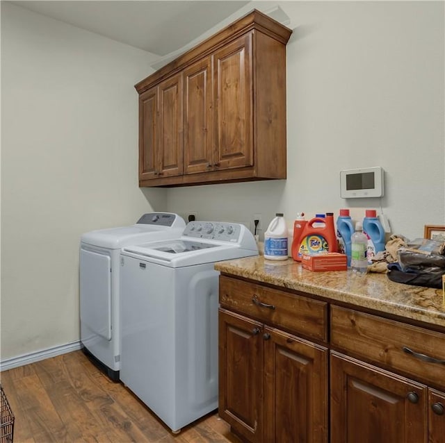 washroom with dark wood-style floors, washer and dryer, cabinet space, and baseboards