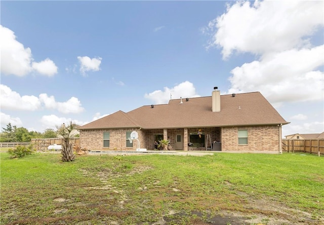 back of property featuring a fenced backyard, brick siding, a lawn, a chimney, and a patio area