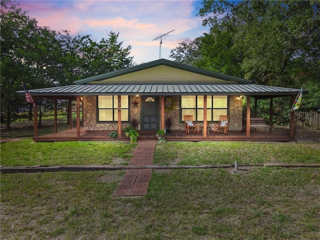 back house at dusk featuring a porch and a yard