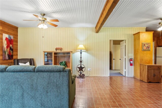 living room with beam ceiling, ceiling fan, and wood walls