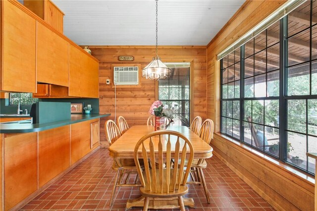 dining space featuring a wall mounted AC, a wealth of natural light, wooden walls, and a notable chandelier