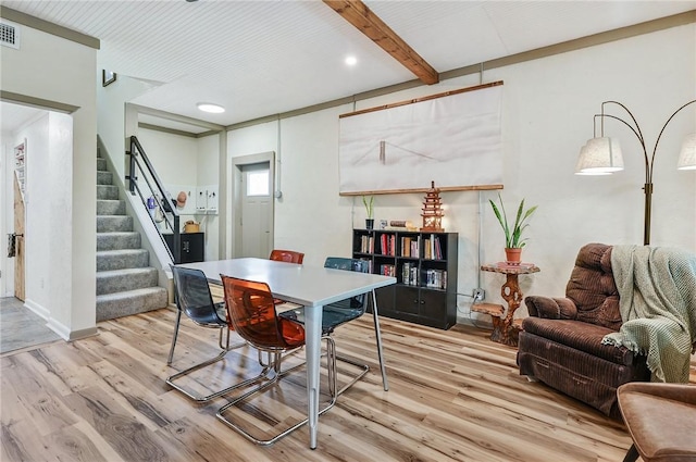 dining room with beamed ceiling and light hardwood / wood-style flooring