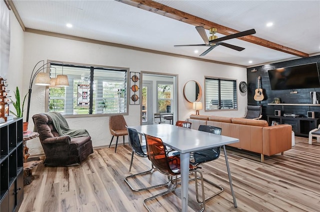 dining room with ceiling fan, light hardwood / wood-style flooring, beamed ceiling, and ornamental molding