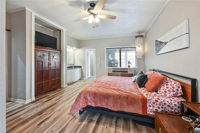 bedroom featuring ensuite bath, ceiling fan, light hardwood / wood-style flooring, and a textured ceiling