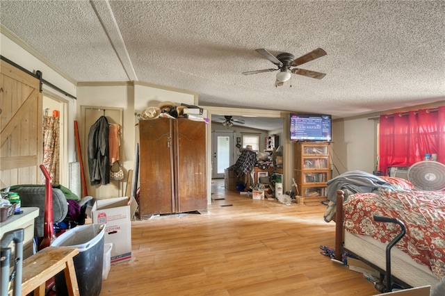 bedroom with ornamental molding, a barn door, a textured ceiling, and light wood-type flooring