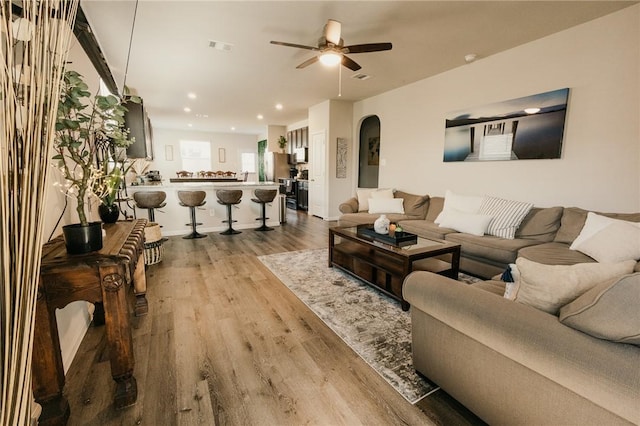 living area featuring visible vents, ceiling fan, recessed lighting, wood finished floors, and arched walkways