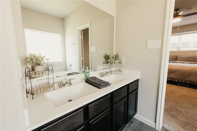 bathroom with a sink, baseboards, ensuite bathroom, and double vanity