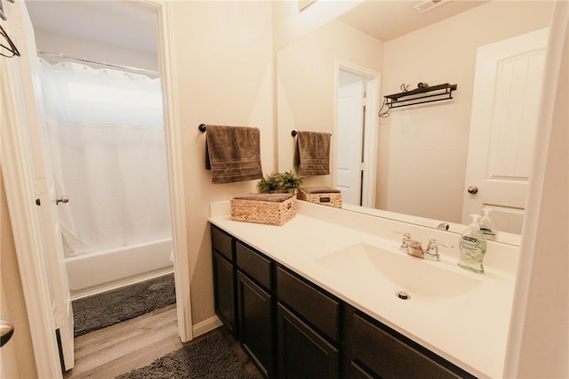 full bath with baseboards, shower / tub combo, wood finished floors, and vanity