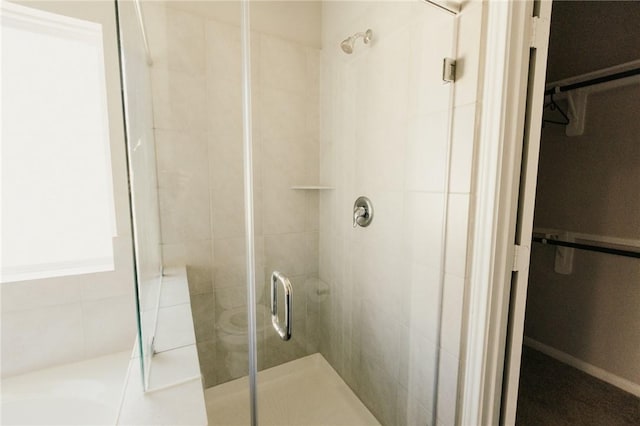 full bathroom featuring a walk in closet, a shower stall, and a garden tub