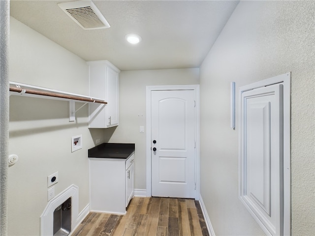 laundry room with dark wood-style flooring, visible vents, cabinet space, electric dryer hookup, and baseboards