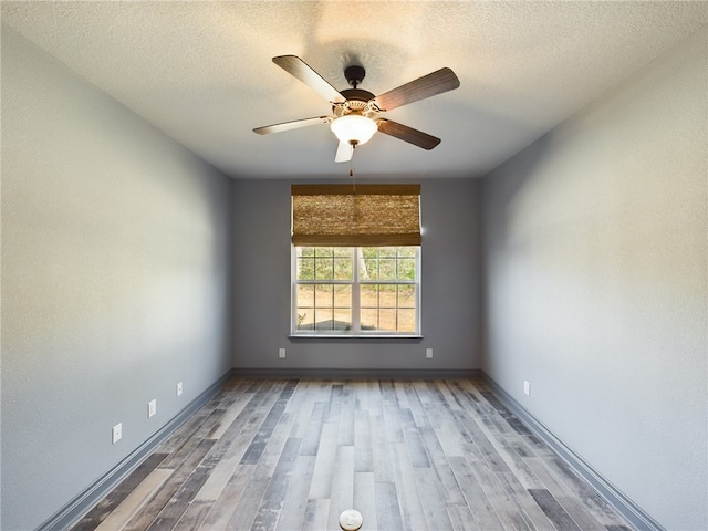 empty room featuring ceiling fan, a textured ceiling, baseboards, and wood finished floors