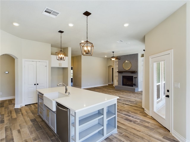 kitchen featuring arched walkways, a center island with sink, light countertops, visible vents, and a sink