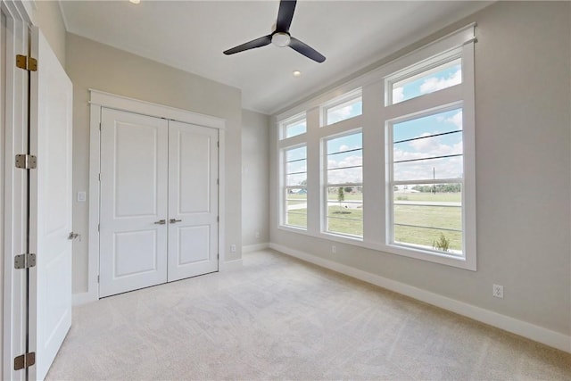 unfurnished bedroom featuring ceiling fan, light carpet, and a closet