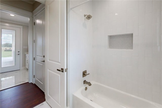 bathroom featuring wood-type flooring and tiled shower / bath