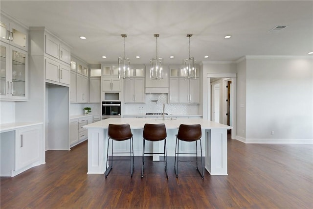 kitchen with white cabinets, dark wood-type flooring, a spacious island, and stainless steel oven