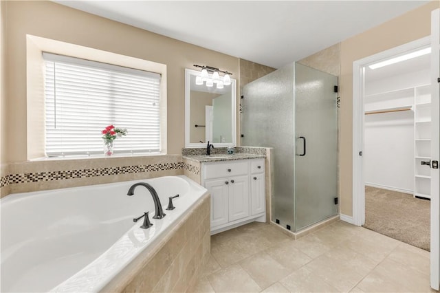 full bath featuring a stall shower, tile patterned flooring, a walk in closet, vanity, and a bath