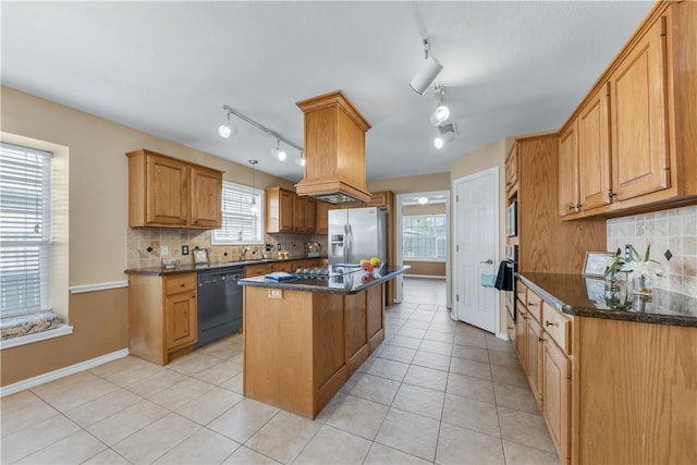 kitchen featuring a center island, tasteful backsplash, appliances with stainless steel finishes, light tile patterned flooring, and dark stone counters