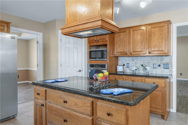 kitchen featuring light tile patterned floors, stainless steel appliances, custom exhaust hood, a center island, and dark stone counters