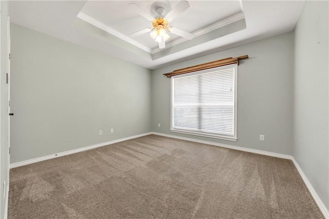 carpeted empty room with crown molding, a raised ceiling, ceiling fan, and baseboards