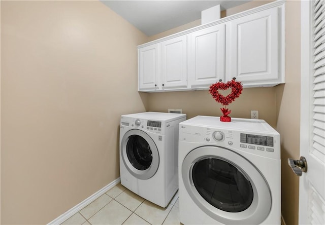 laundry area featuring light tile patterned floors, washing machine and dryer, cabinet space, and baseboards