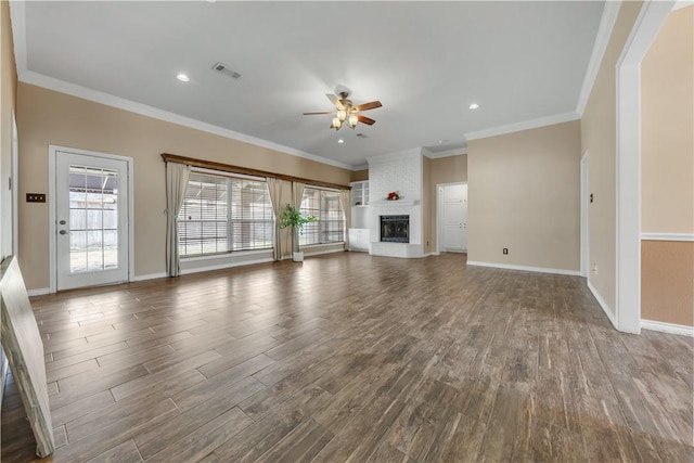 unfurnished living room with a fireplace, wood finished floors, visible vents, a ceiling fan, and crown molding