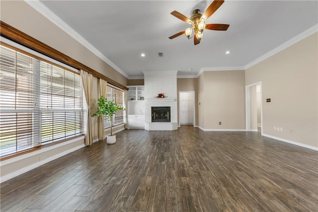 unfurnished living room with dark wood-type flooring, a brick fireplace, ornamental molding, and baseboards