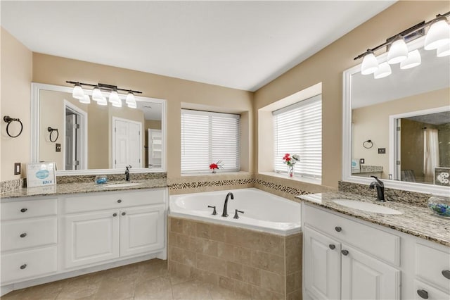 full bathroom with tile patterned flooring, two vanities, a sink, and a bath